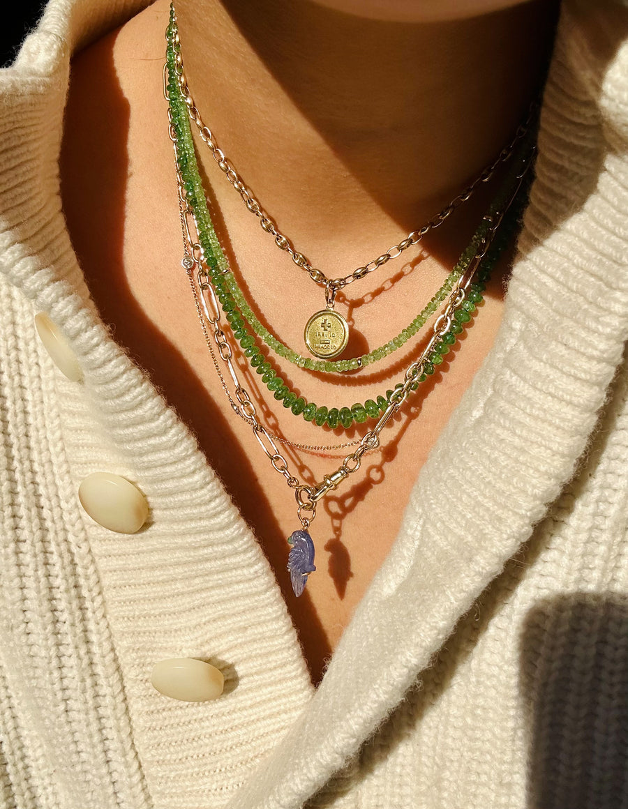 Two tsavorite garnet necklaces. One is smaller, thinner and lighter in color. The smaller one is also faceted and has little gold beads. The second necklace has smooth and bigger beds. Its darker in color and longer